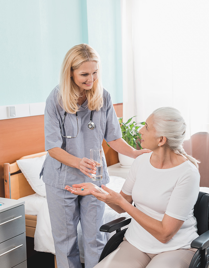 smiling-nurse-giving-glass-of-water-to-disabled-se-4JDRBJR